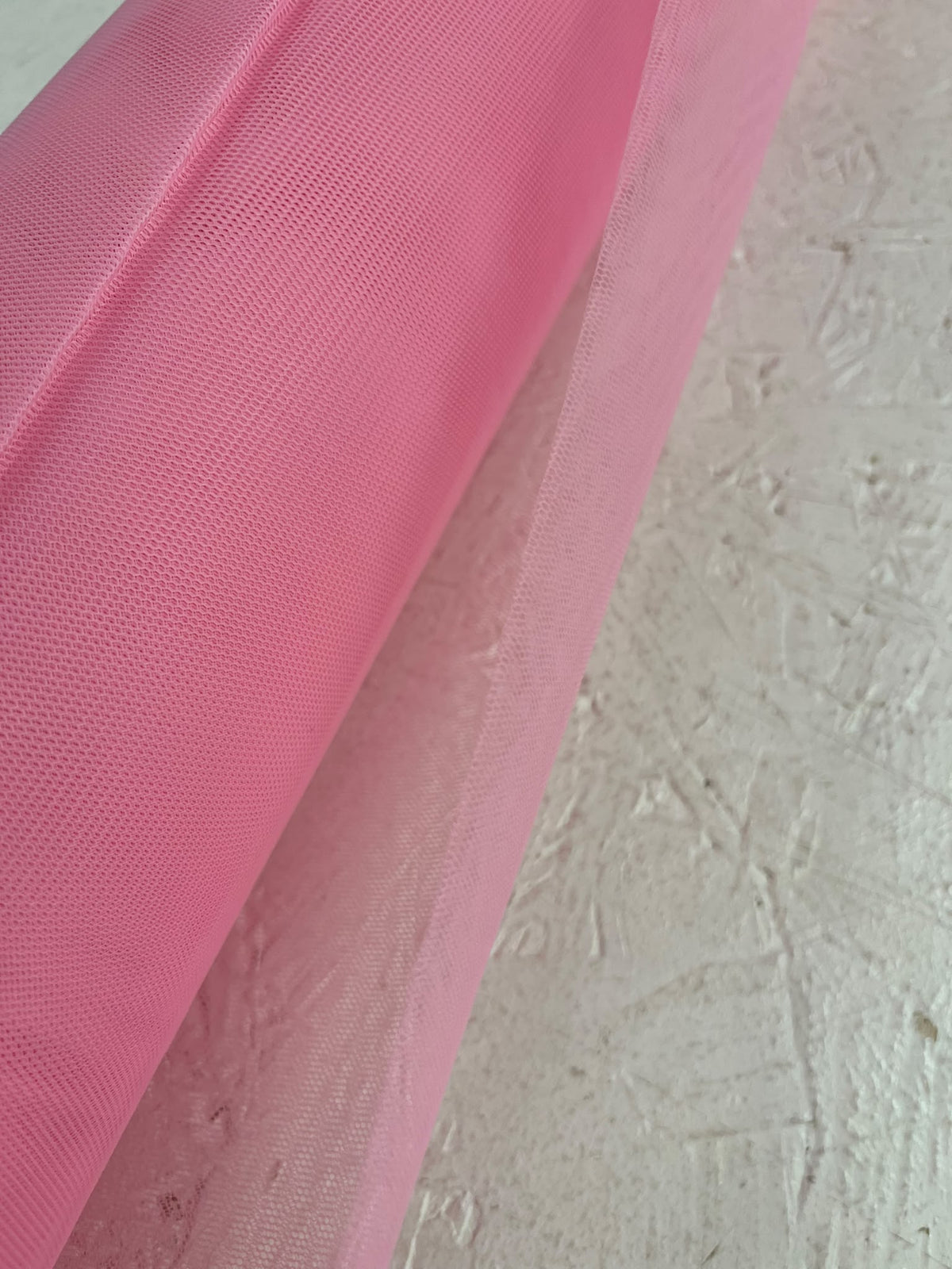 Tul rosa de trama fina y transparente junto al rollo