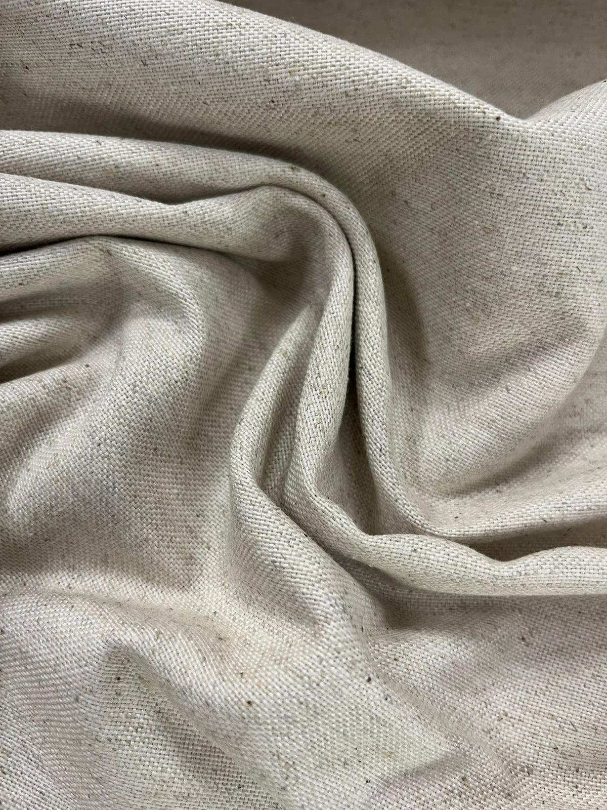 Loneta beige jaspeada con pliegues, trama visible y pequeñas motas oscuras