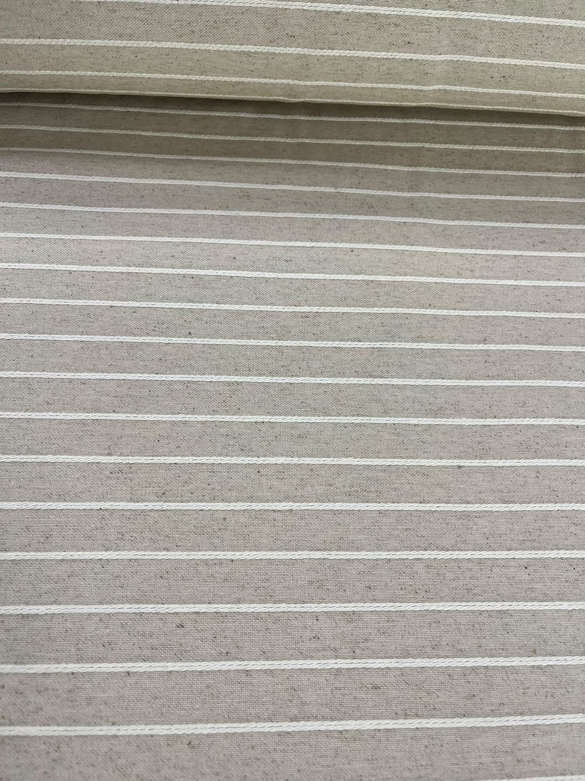 Loneta beige de rayas tejidas extendida junto al rollo