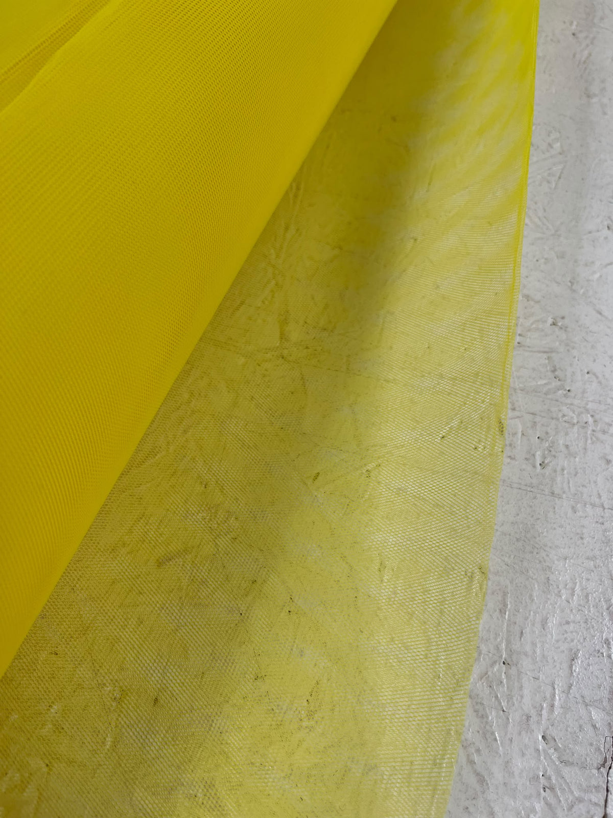 Tul amarillo de trama fina y transparente junto al rollo
